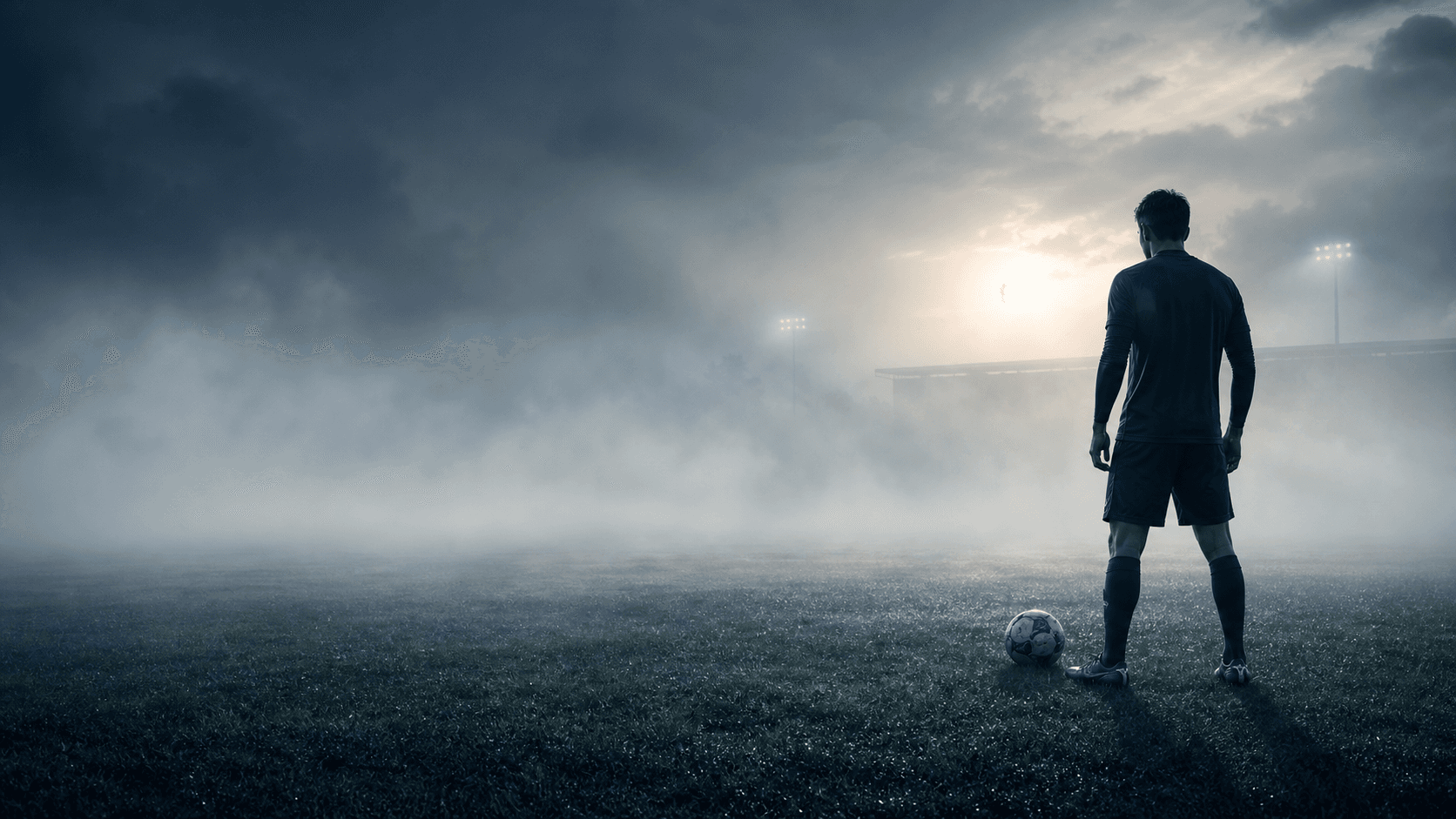 A fictional footballer on a foggy morning football pitch.